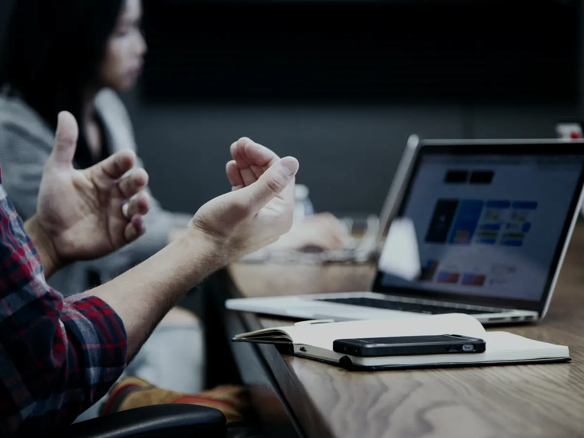 Dos personas conversando sobre un problema frente a una laptop