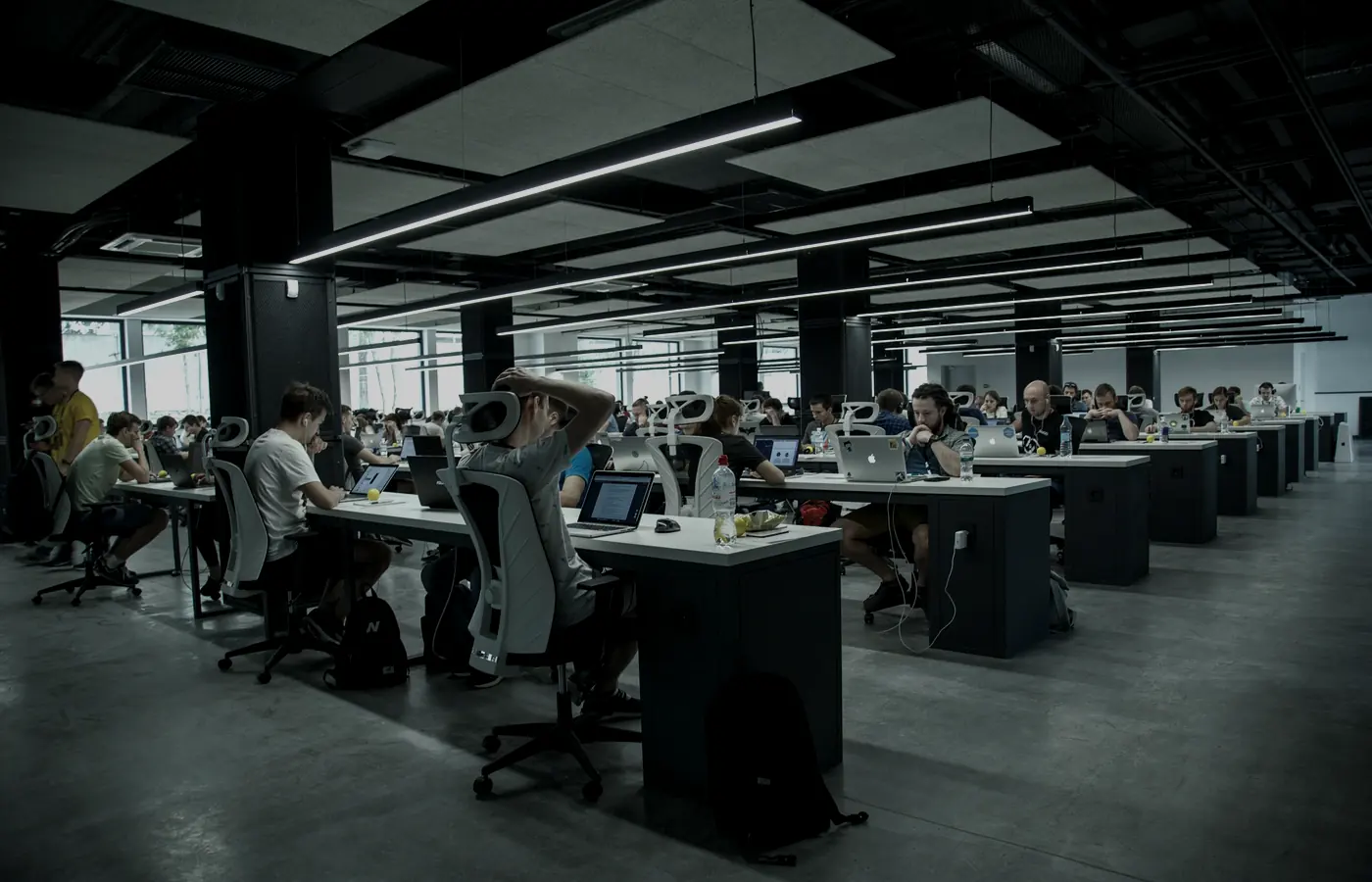 Un piso amplio de oficina abierta con gente trabajando en escritorios compartidos
