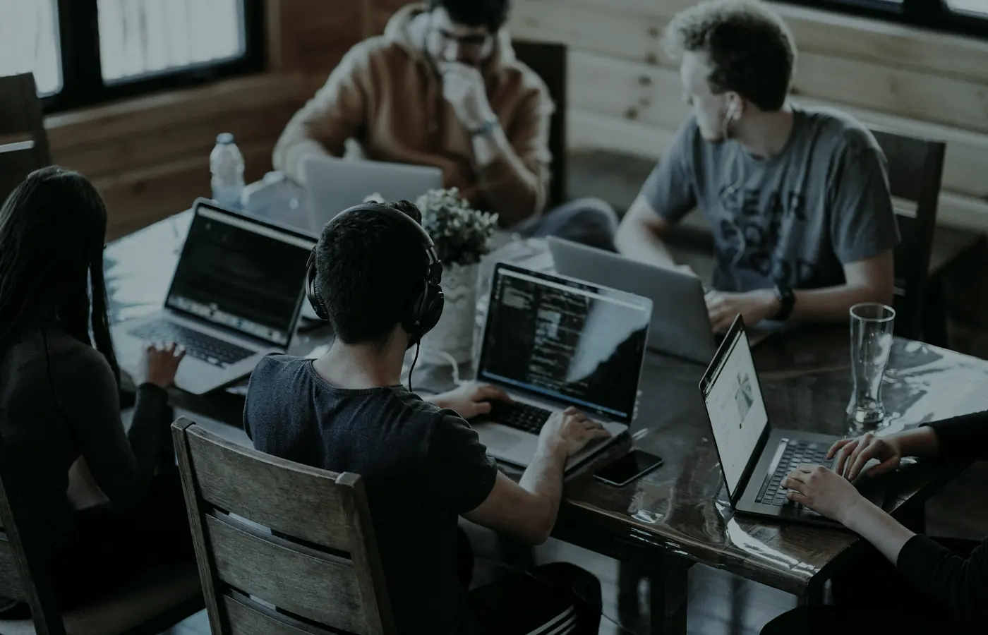 Un equipo fundador pequeño trabajando codo a codo alrededor de una mesa