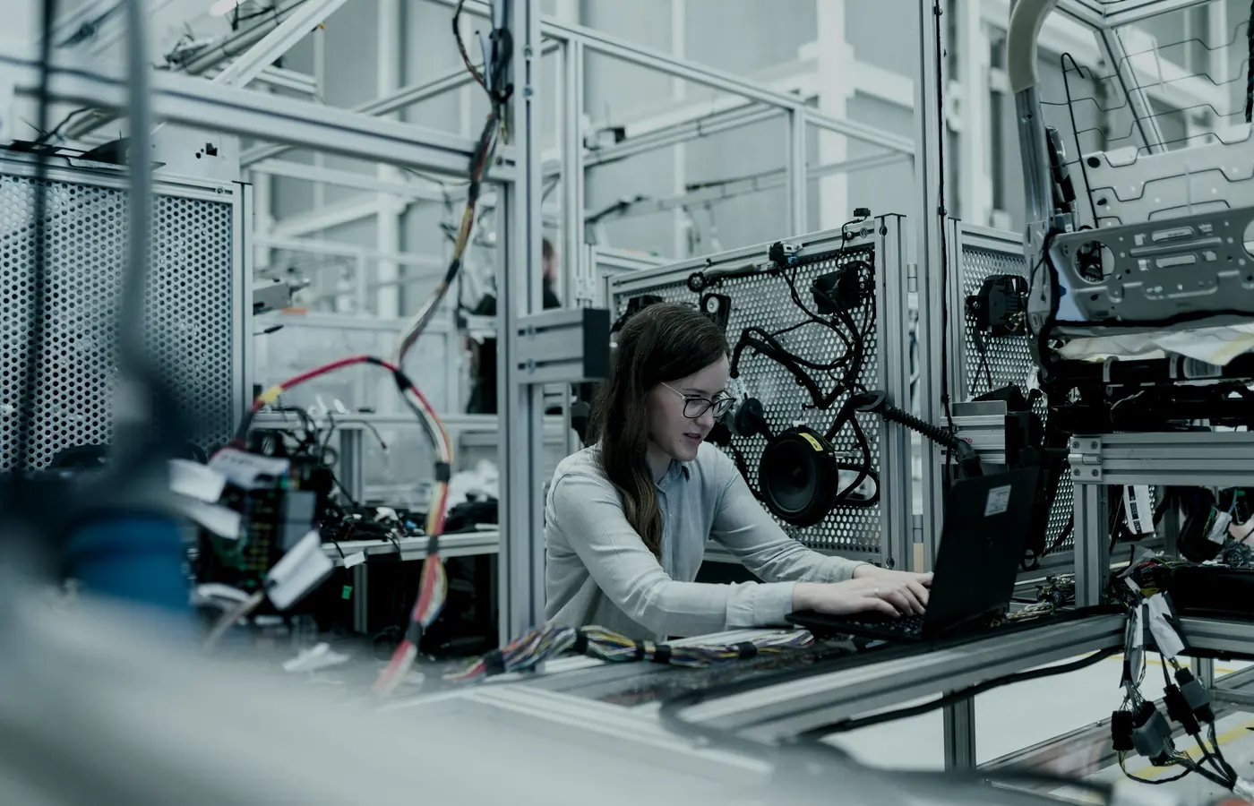 Un ingeniero con una laptop junto a una línea de producción automatizada